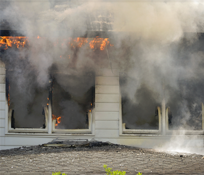 smoke and fire billowing out of a window of a house